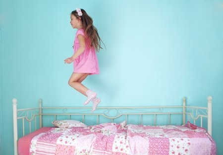 girl jumping on bed